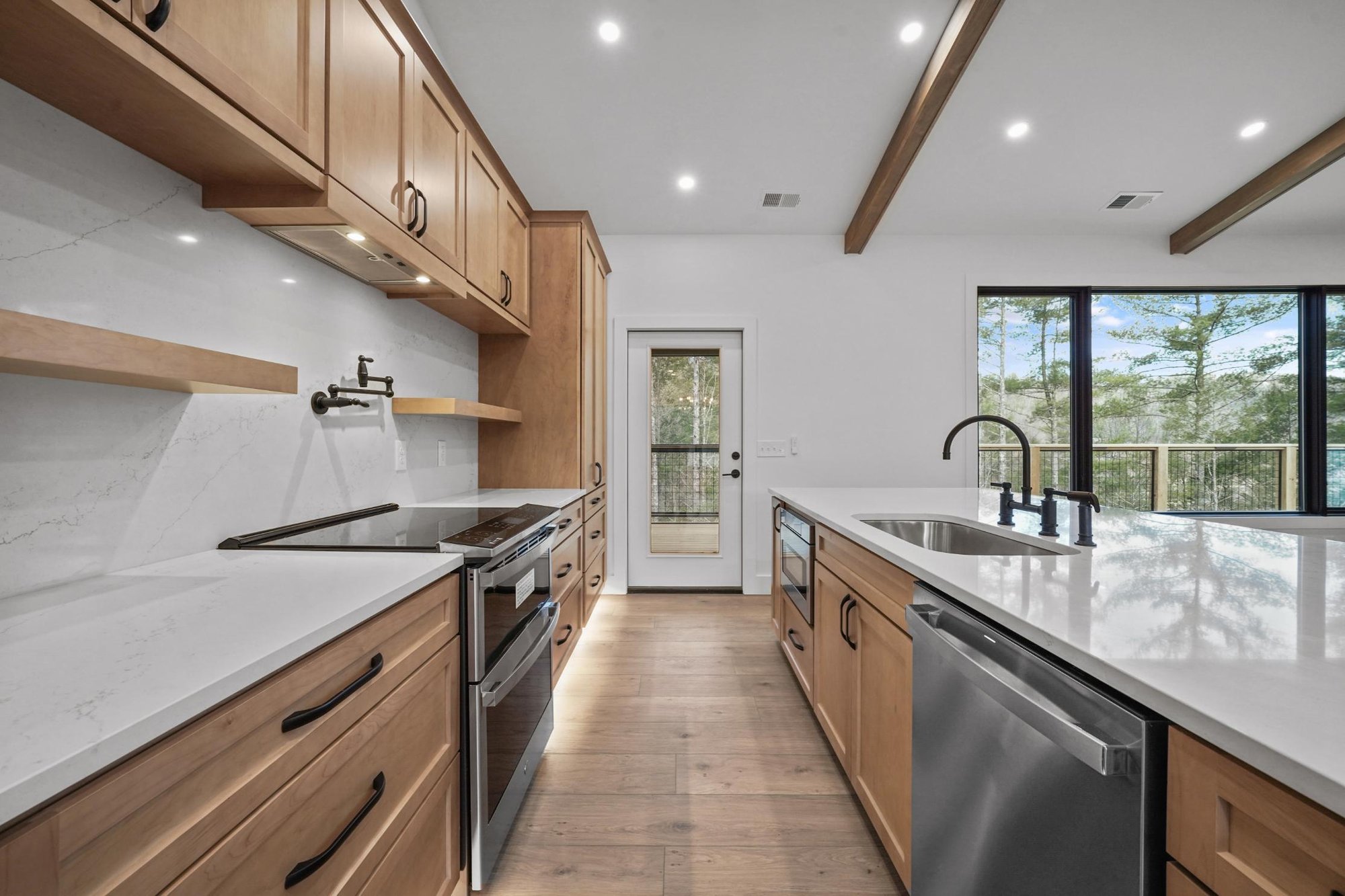 Open kitchen with exposed beams, stainless steel appliances, and white subway tile in a custom home in Townsend, TN, by Debuty Builders, Inc.