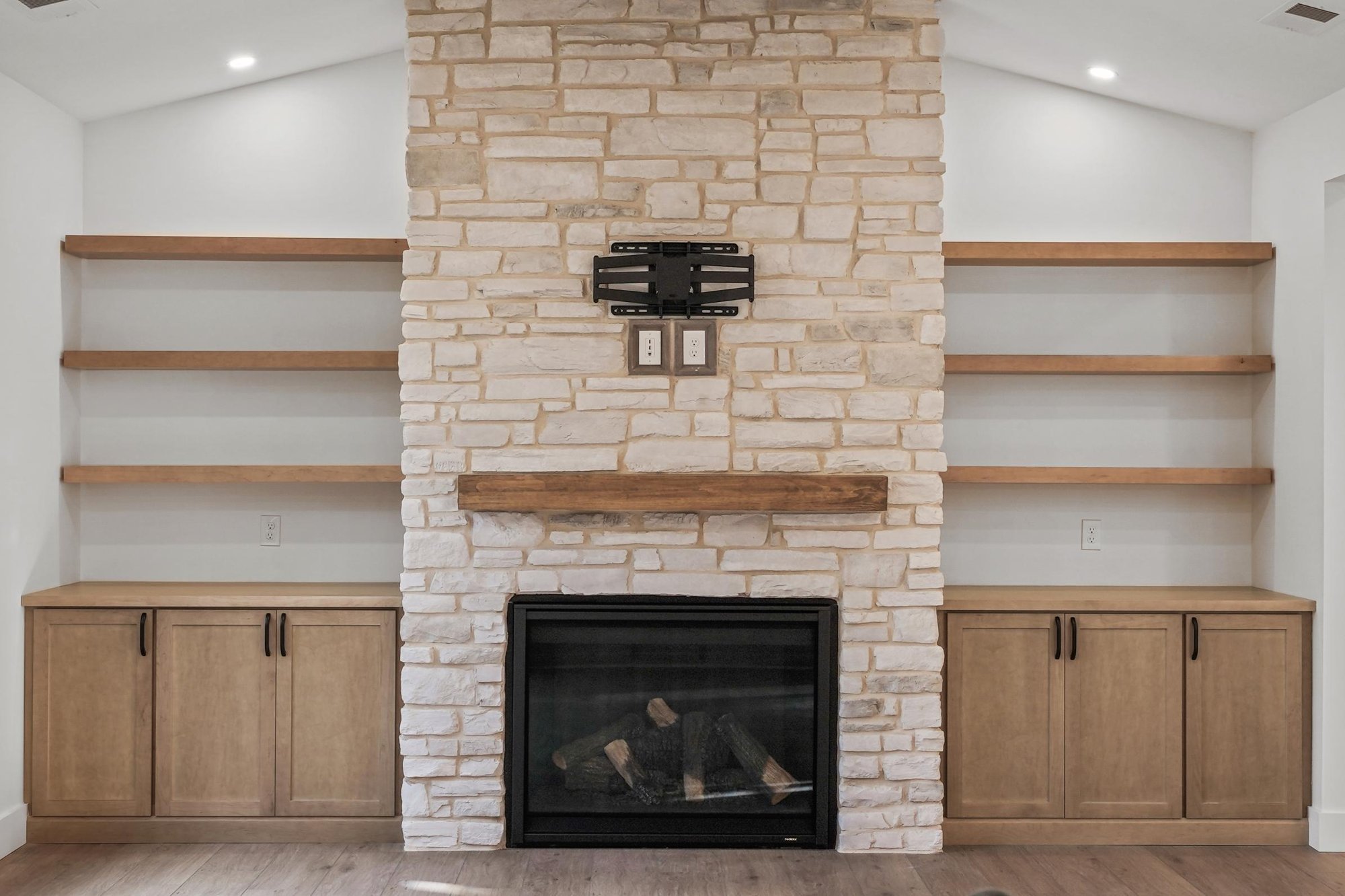 tall, natural stone fireplace, floating shelves, built in cabinetry, LVP flooring