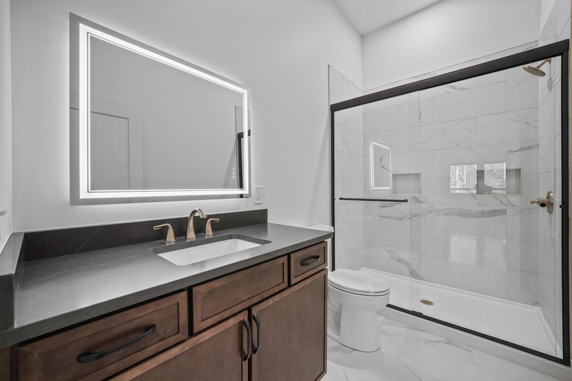 High-end tile white shower with black and walnut vanity and gold features in a custom home by Debuty Builders, Inc.