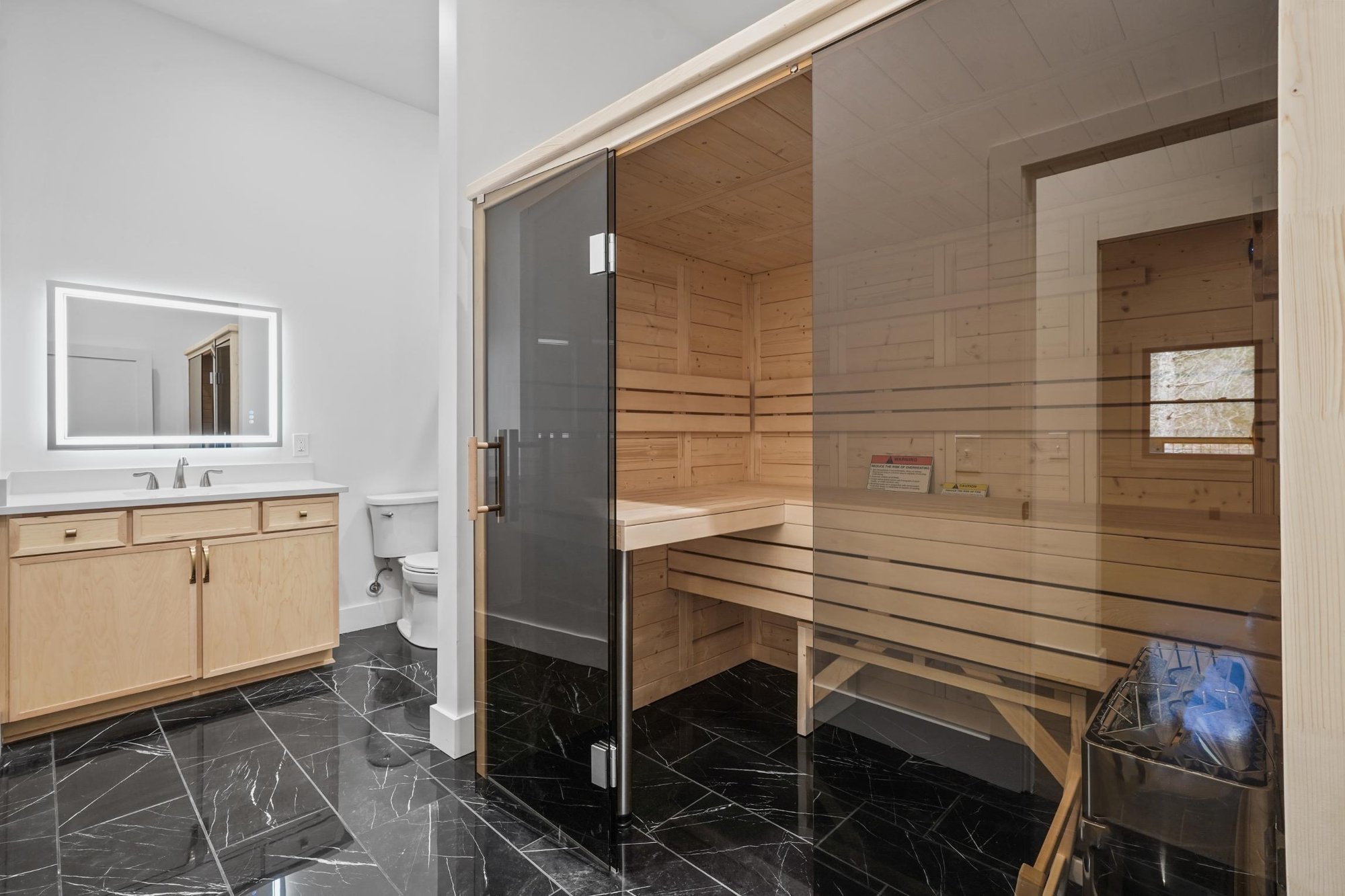 luxury black tile, light wood vanity, and built in sauna in custom home in Townsend, TN