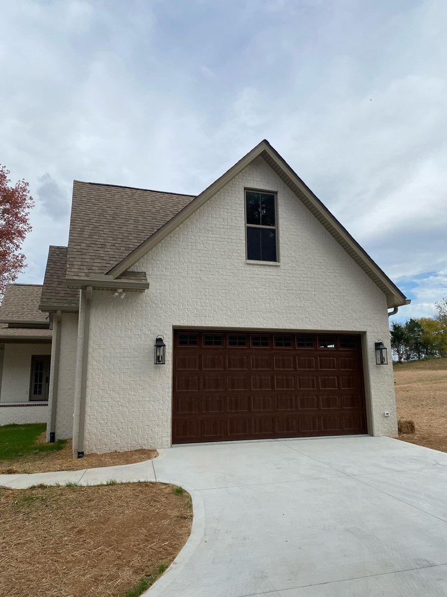 White brick exterior with dark wood garage door in a custom home by Debuty Builders, Knoxville, TN