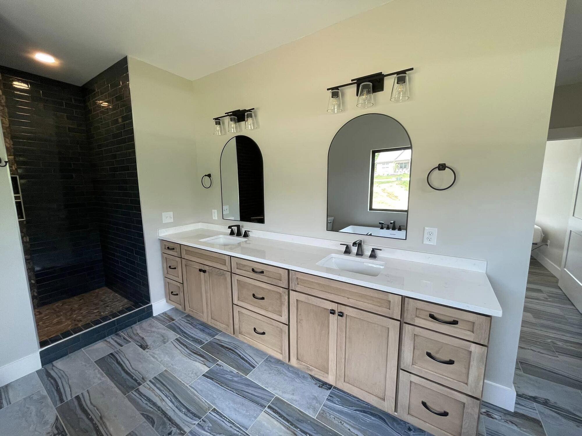 Modern bathroom remodel by Debuty Builders featuring double vanity with sleek black fixtures in Knoxville, TN