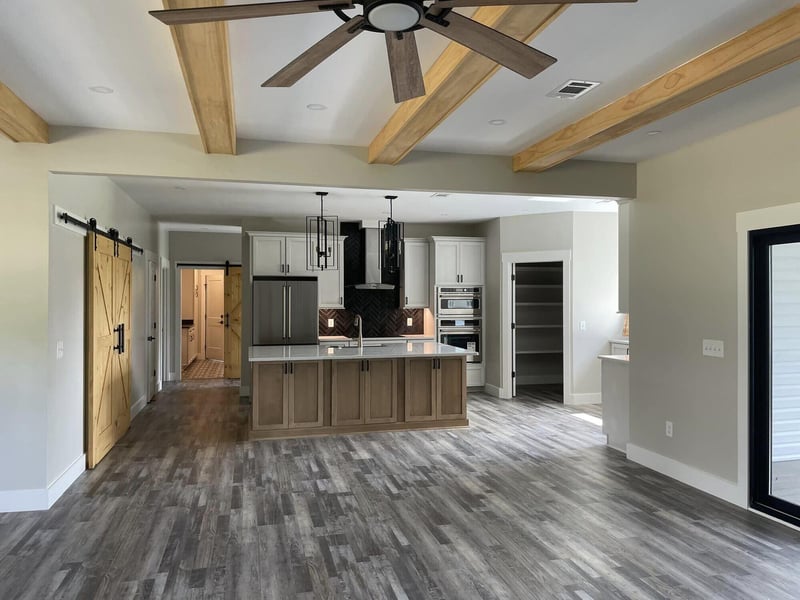 Open kitchen with wood beams and barn doors in a remodel by DeButy Builders, Knoxville, TN