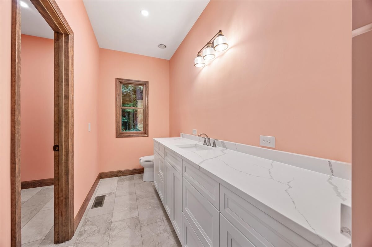 Bright bathroom with coral walls and white double vanity in Friendsville Custom Home in Knoxville, TN