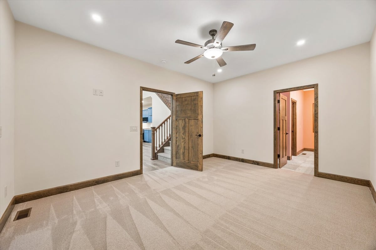 Carpeted bedroom with ceiling fan and two doorways in Friendsville Custom Home in Knoxville, TN