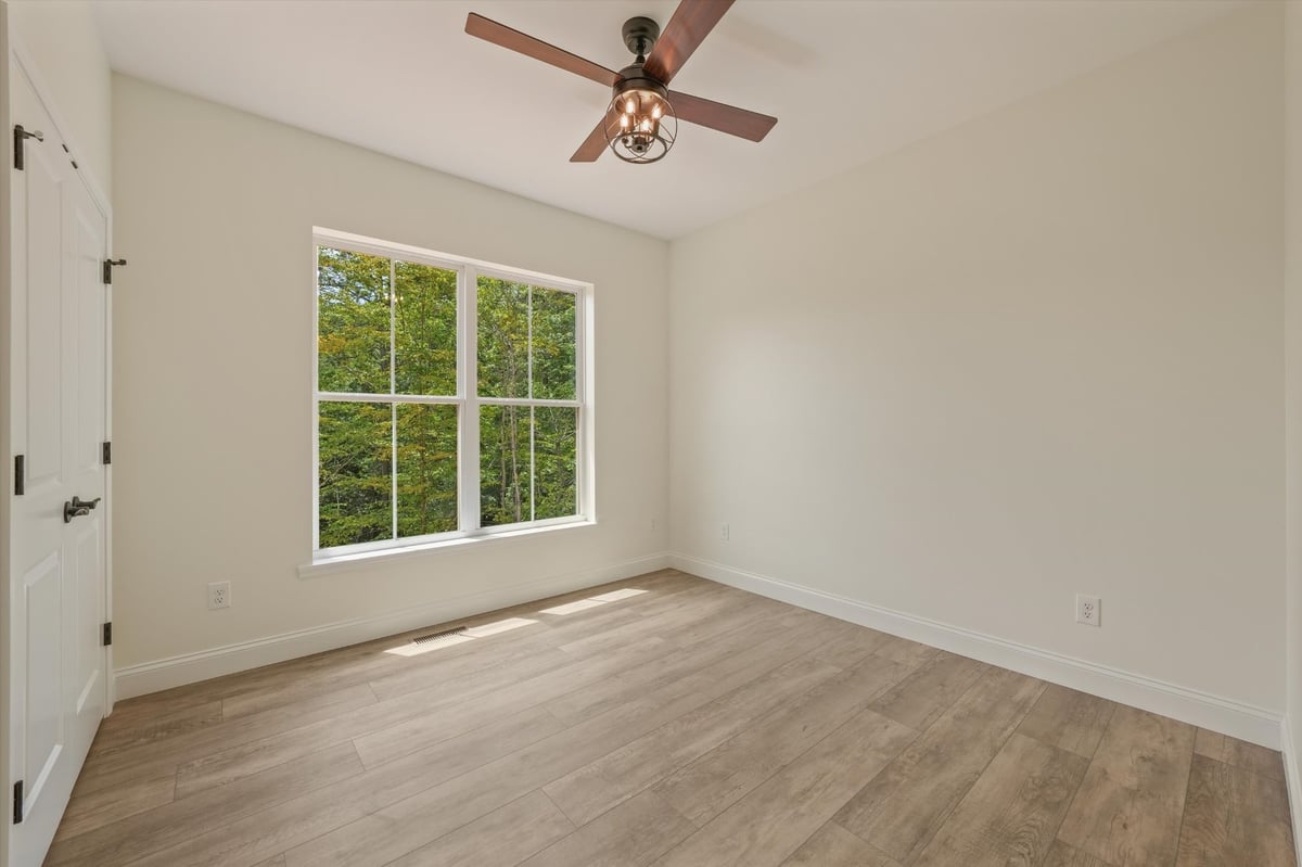 custom home bedroom with large window wood look flooring and ceiling fan in maryville tn