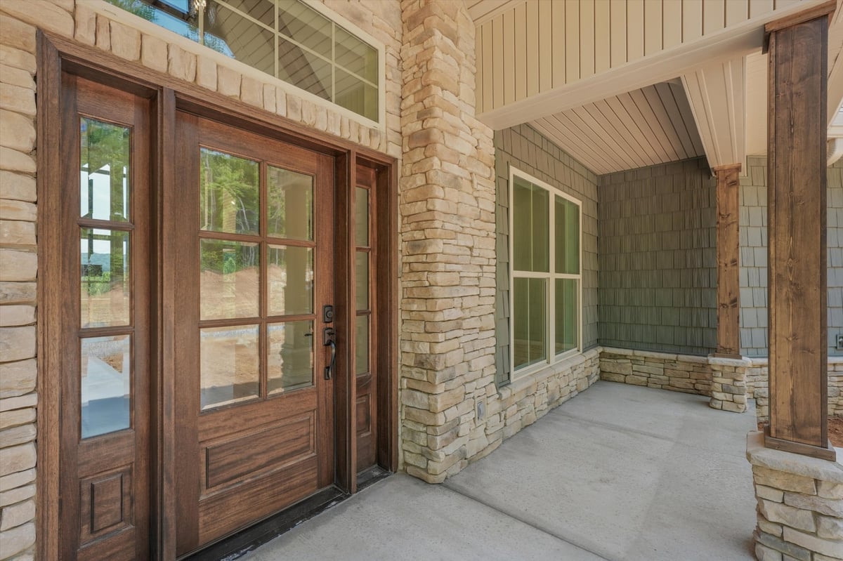 custom home covered front porch with wood glass door and stone accents in maryville tn
