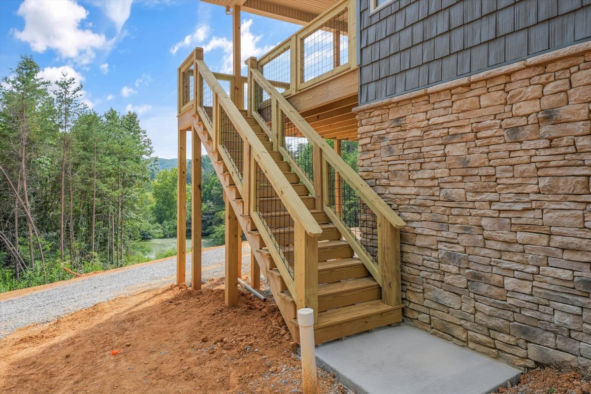 custom home exterior wood staircase beside stone siding in maryville tn