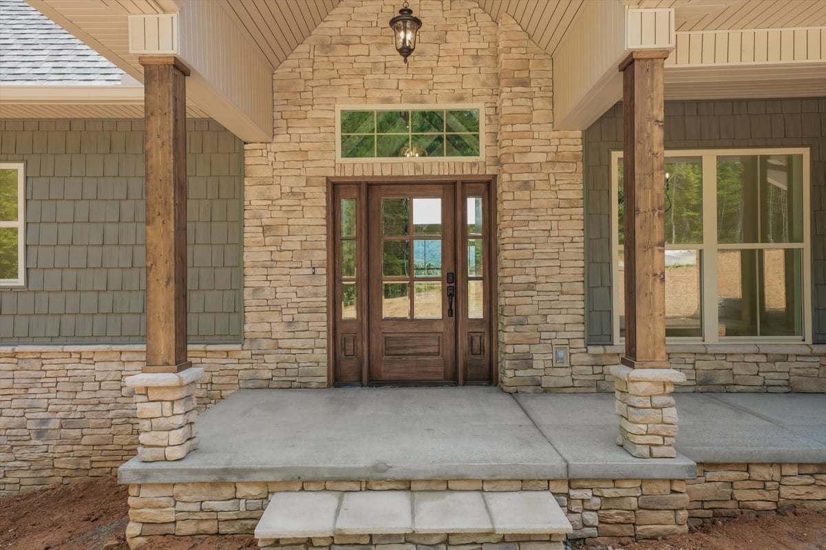custom home front porch with stone entry wood columns and glass front door in maryville tn
