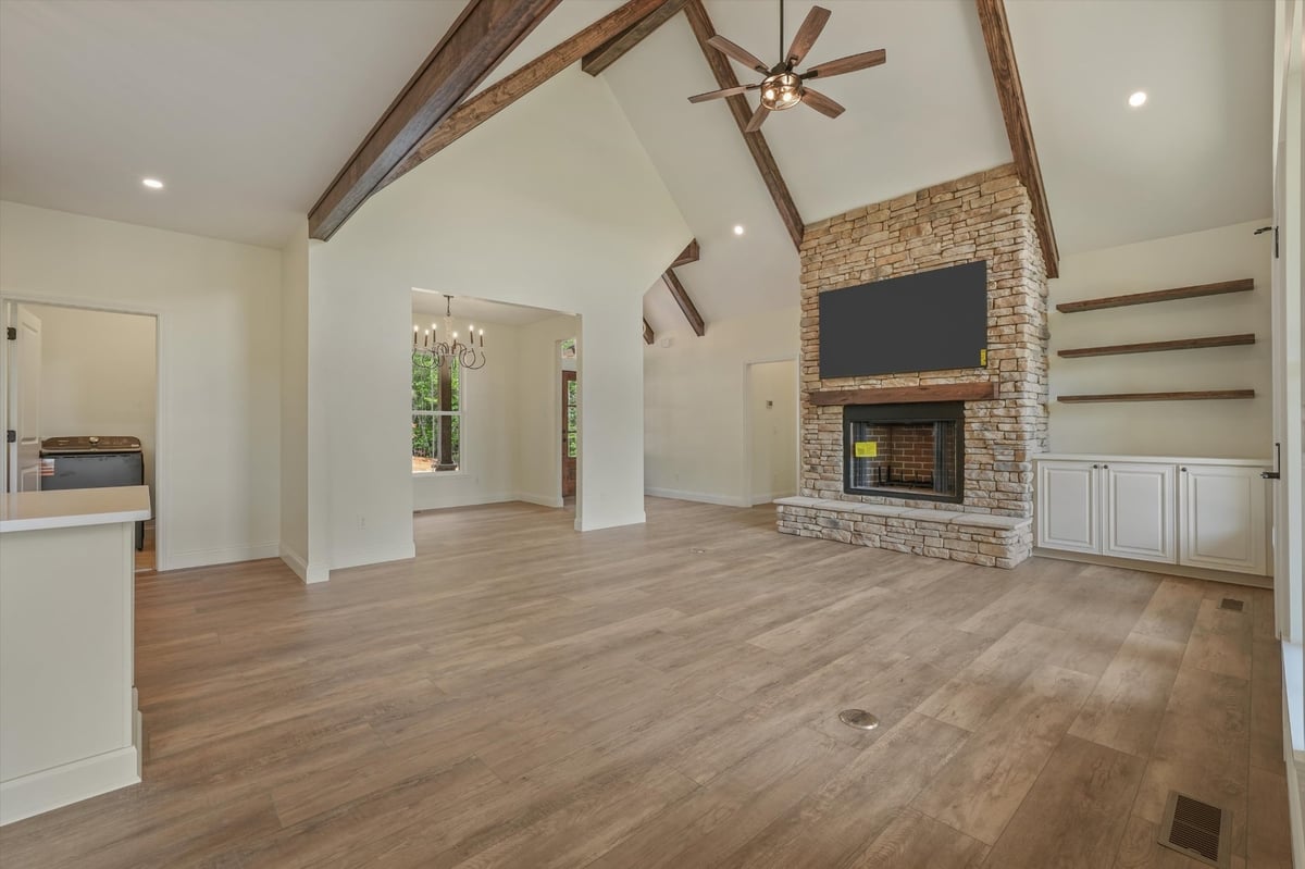 custom home great room with stone fireplace exposed beams and built in shelving in maryville tn