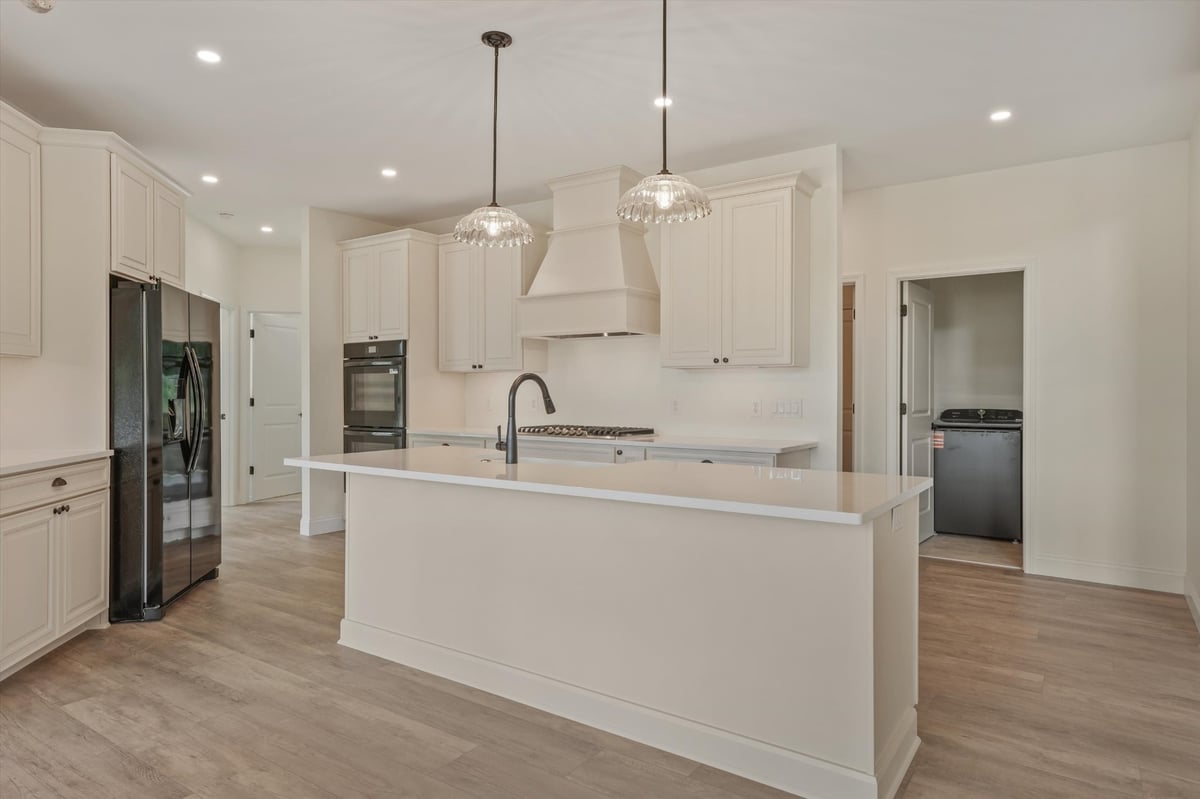 custom home kitchen with white cabinetry large island and custom range hood in maryville tn