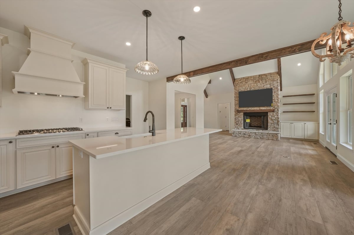 custom home open kitchen and living room with white island stone fireplace and exposed beams in maryville tn