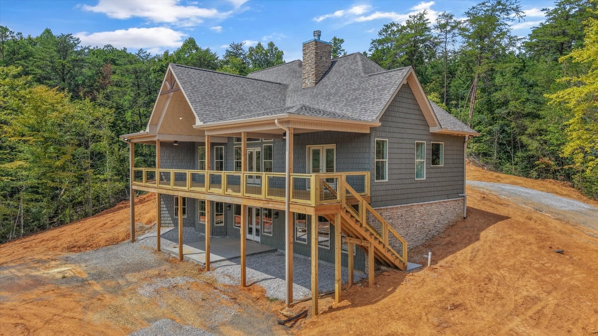 custom home rear exterior with covered deck stone accents and wooded setting in maryville tn