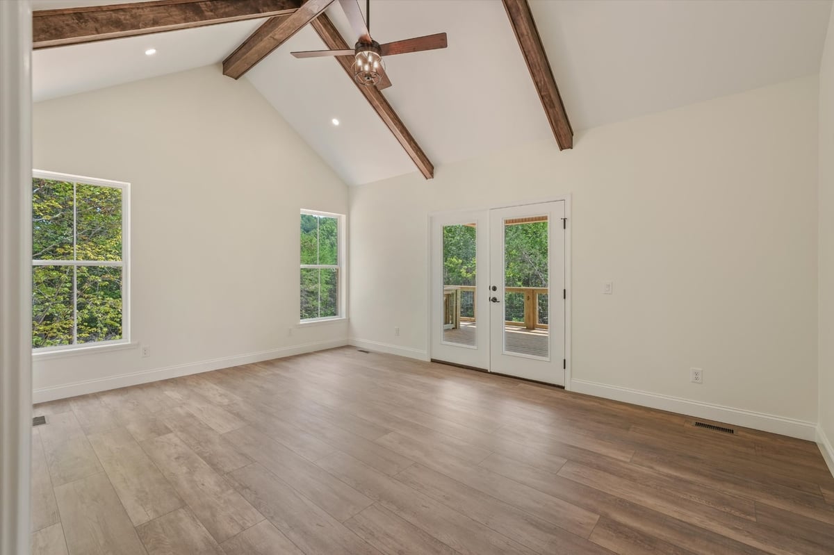 custom home room with vaulted ceiling exposed wood beams and deck access in maryville tn