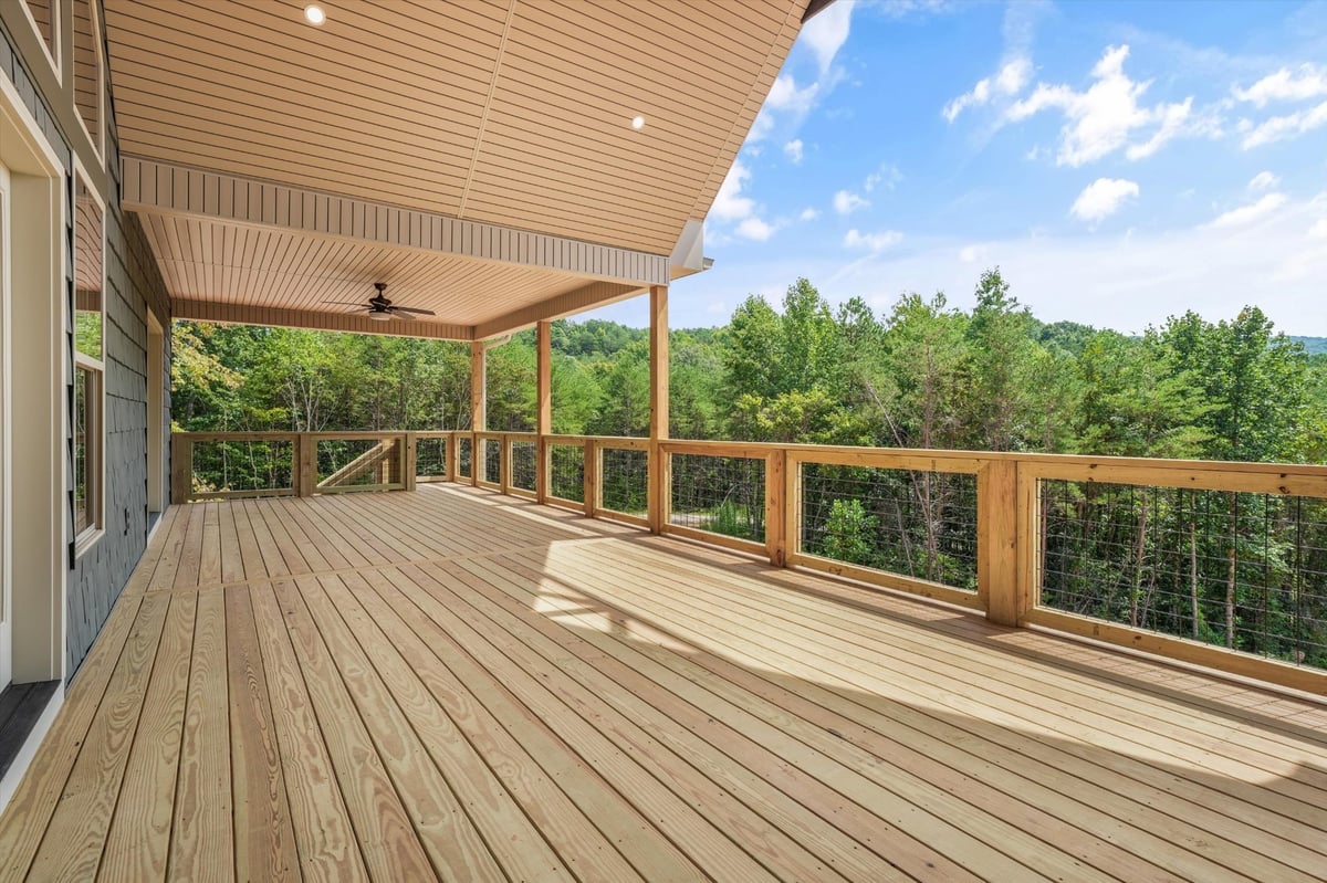 custom home spacious covered deck with wood railing and forest views in maryville tn