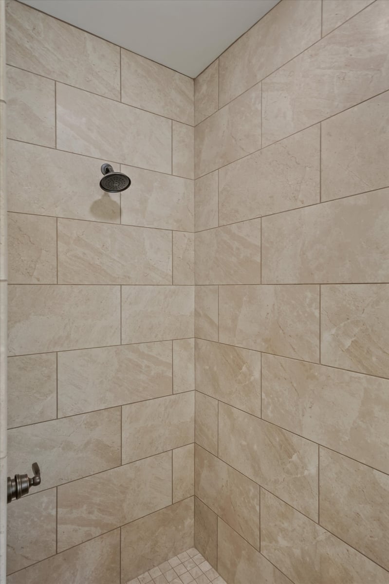 custom home walk in shower with large beige tile and dark showerhead in maryville tn