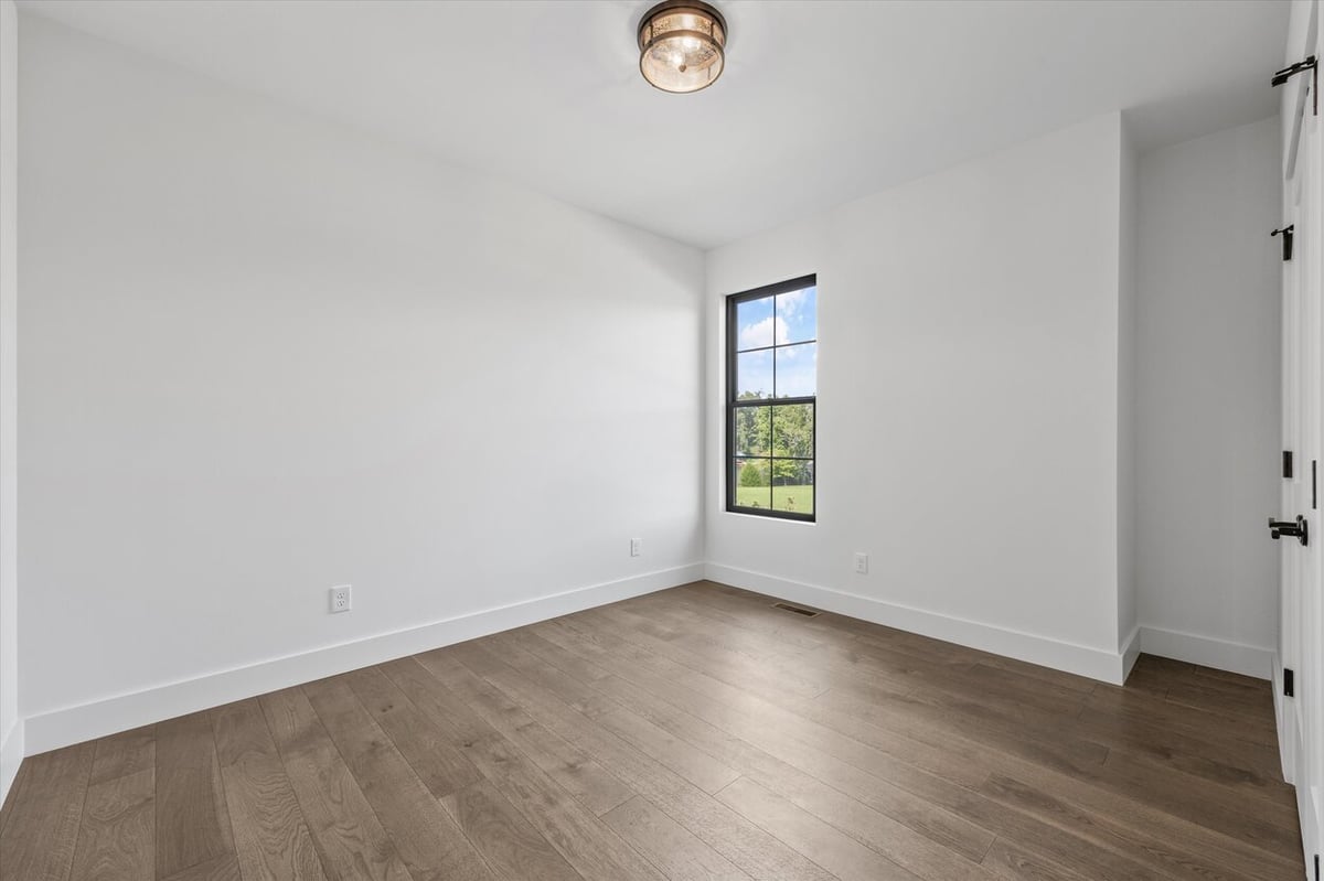 Additional bedroom in a Louisville, TN custom home with hardwood floors and large window
