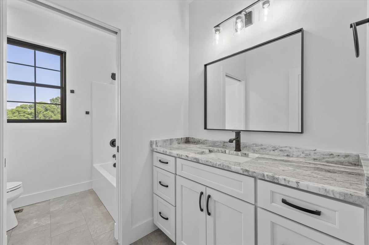 Bathroom in a Louisville, TN custom home with granite countertop, white cabinetry, and black fixtures