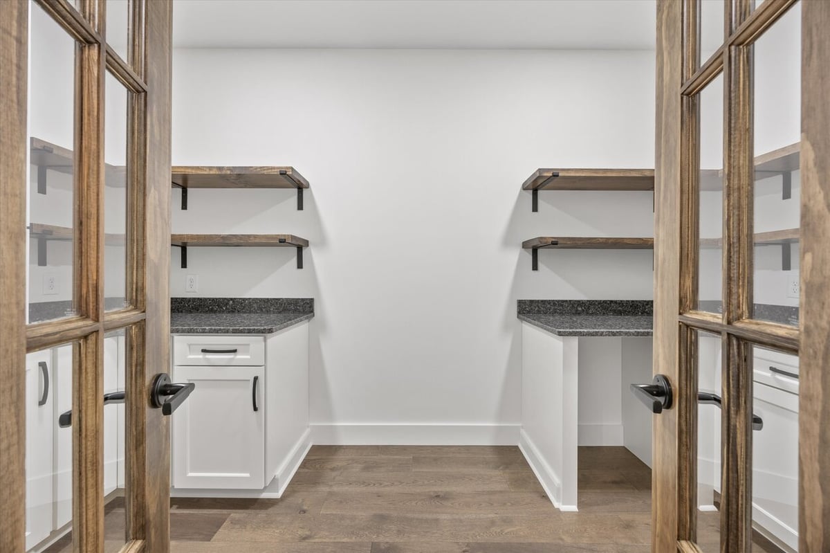 Built-in pantry space in a Louisville, TN custom home with dark countertops and wood shelving