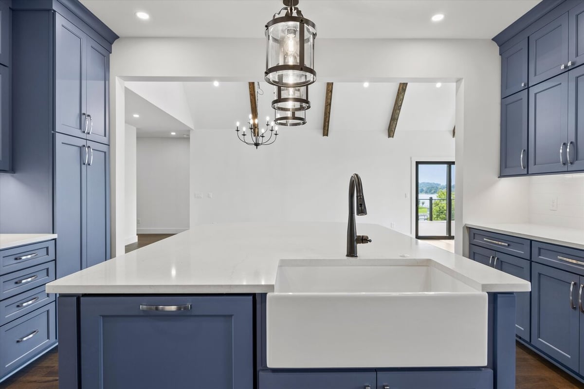 Close-up of kitchen sink and island in a Louisville, TN custom home with blue cabinets and quartz counters