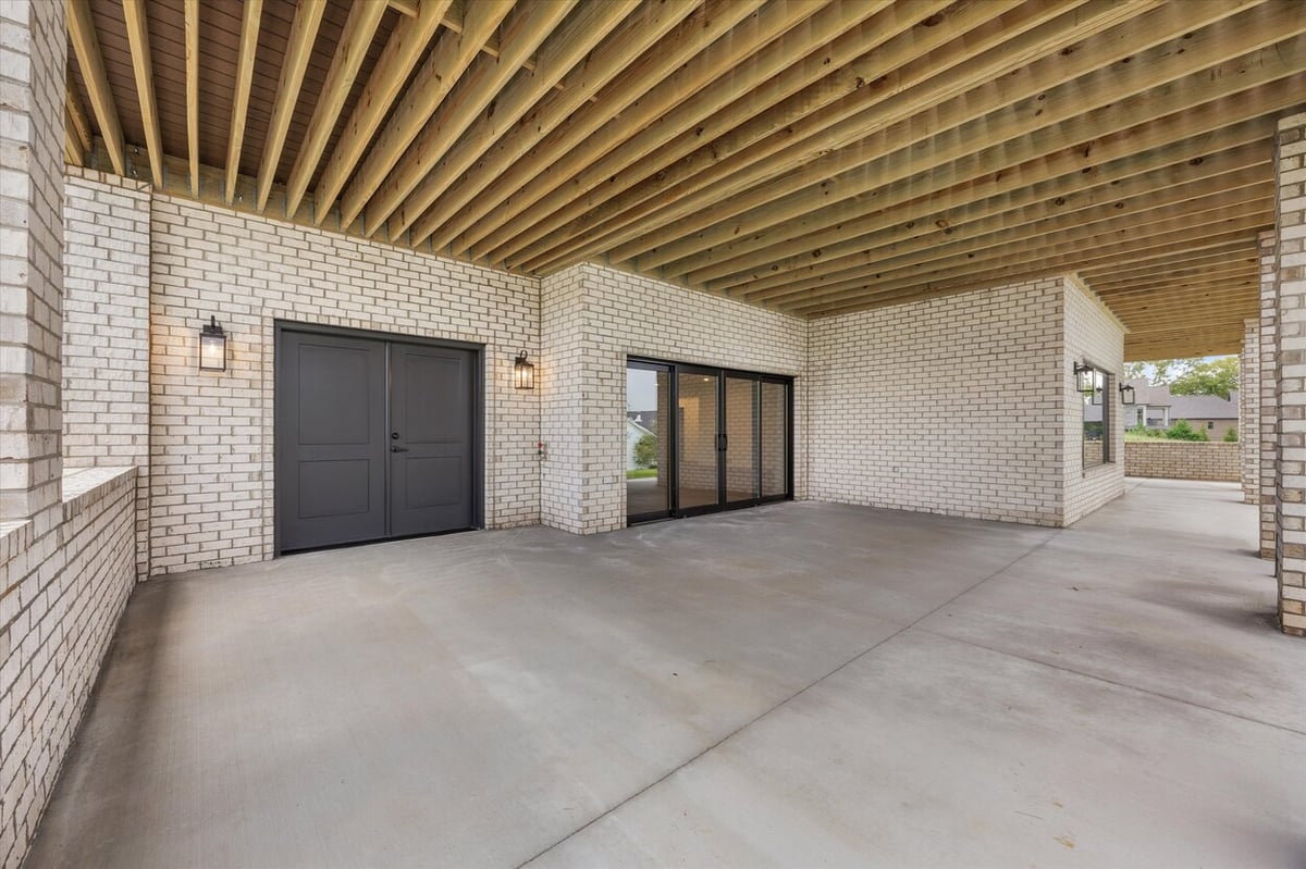 Covered outdoor patio area in a Louisville, TN custom home with white brick exterior and black double doors