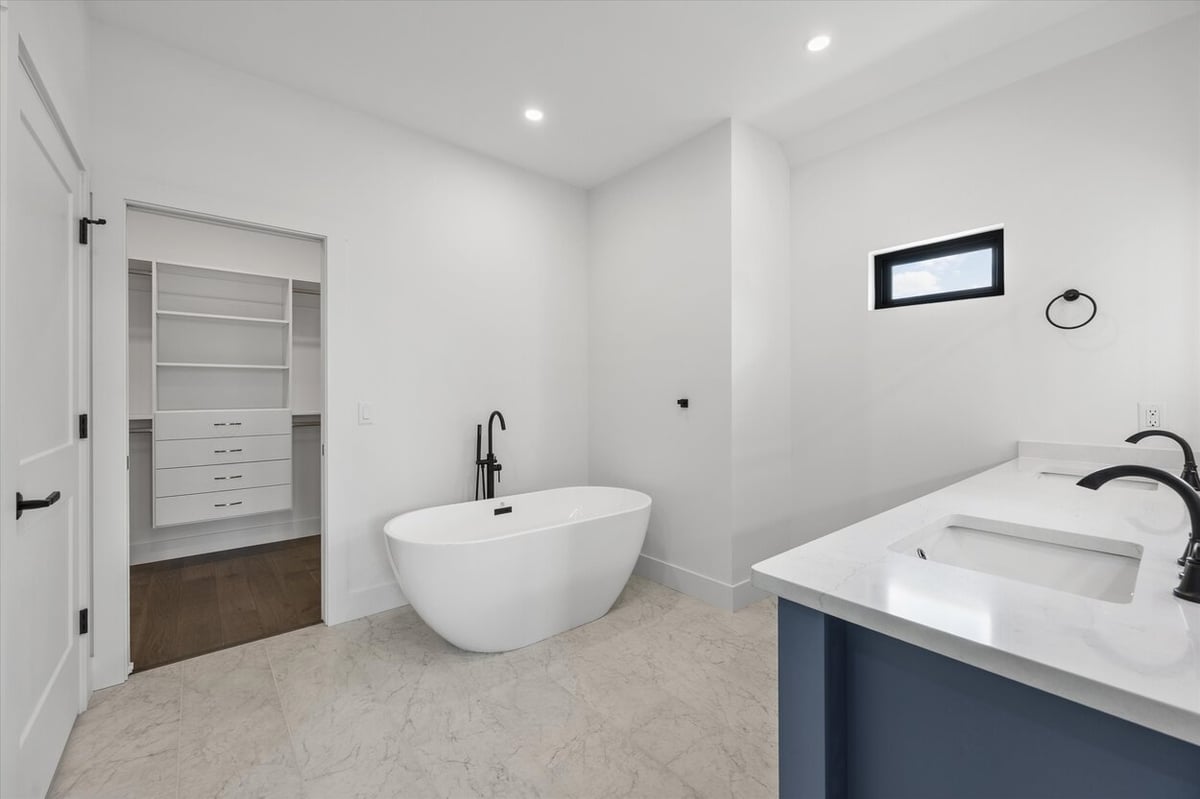 Freestanding soaking tub with black fixtures in a Louisville, TN custom home primary bath