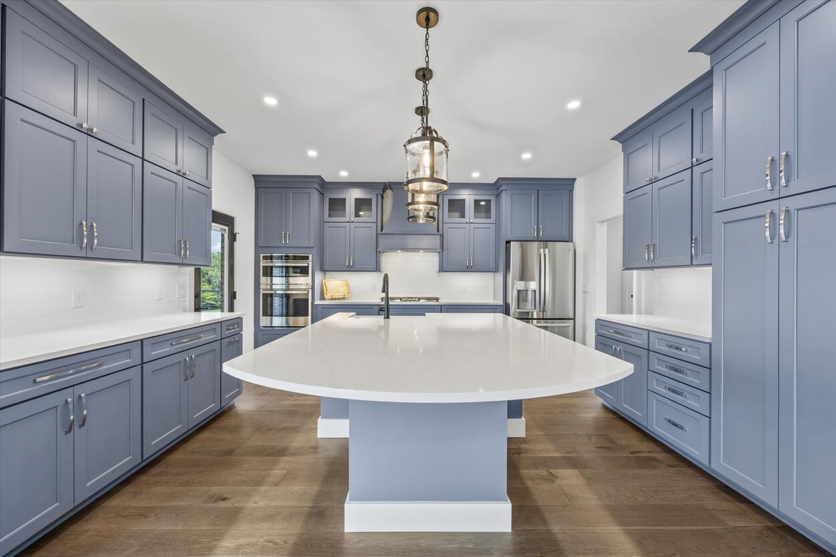Gourmet kitchen in a Louisville, TN custom home with navy cabinets, pendant lighting, and oversized island