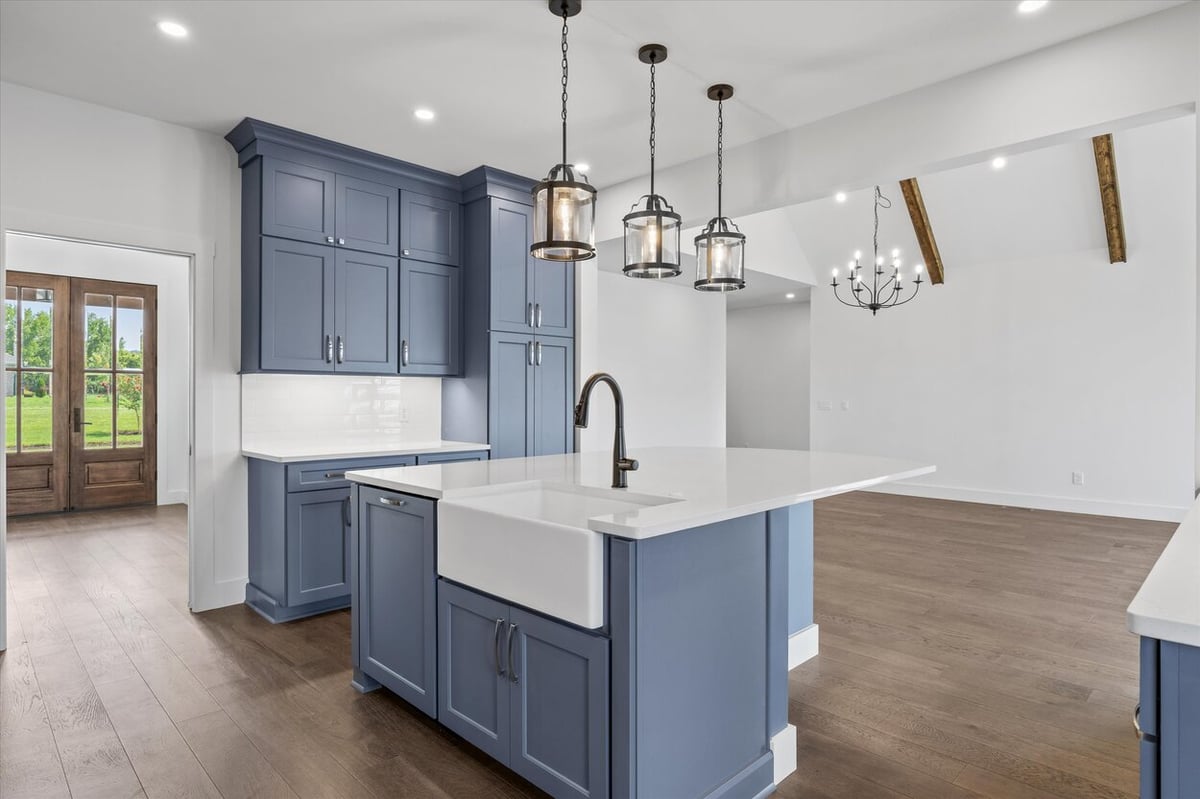 Kitchen island and pendant lighting in a Louisville, TN custom home featuring blue cabinetry and a farmhouse sink