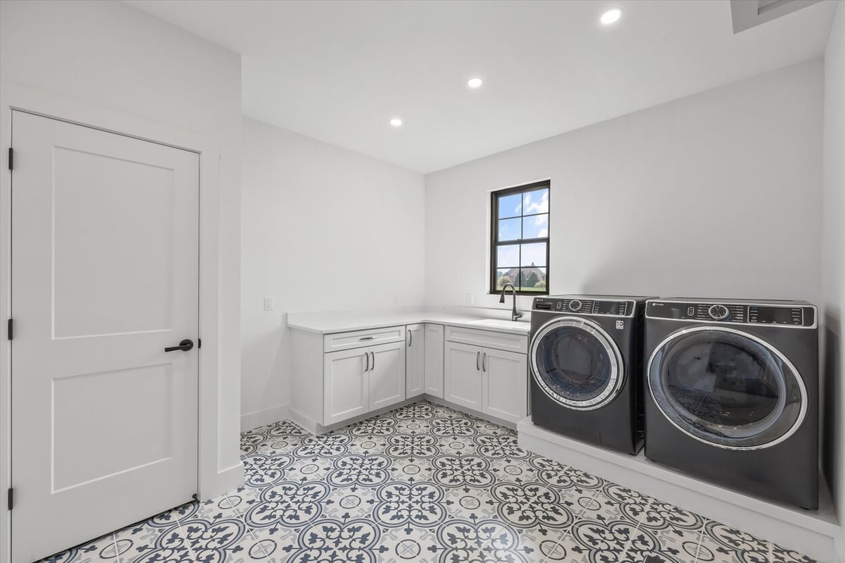 Laundry room in a Louisville, TN custom home with patterned tile flooring and modern washer and dryer