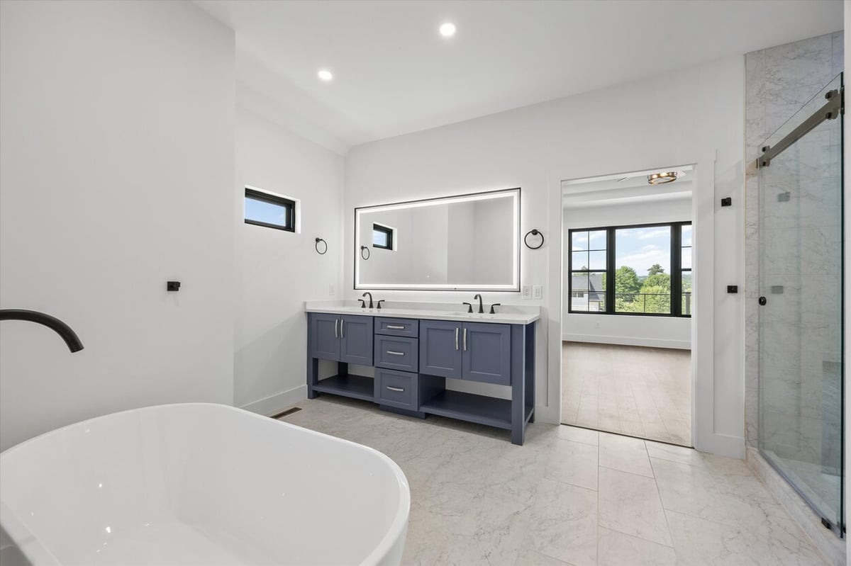 Primary bathroom in a Louisville, TN custom home with freestanding tub, dual vanity, and LED mirror