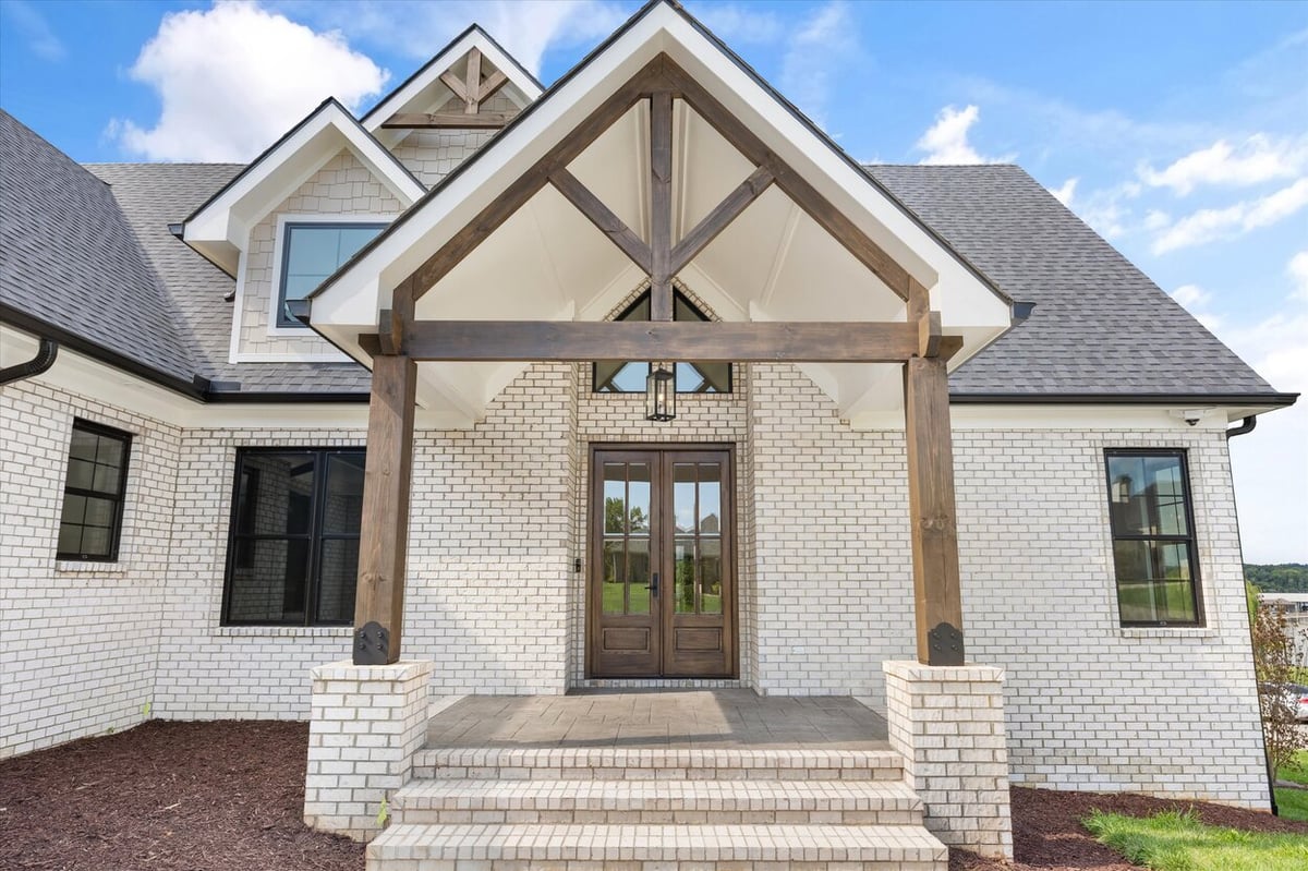 Rustic wood and brick entry of a Louisville, TN custom home with gabled porch and double front doors