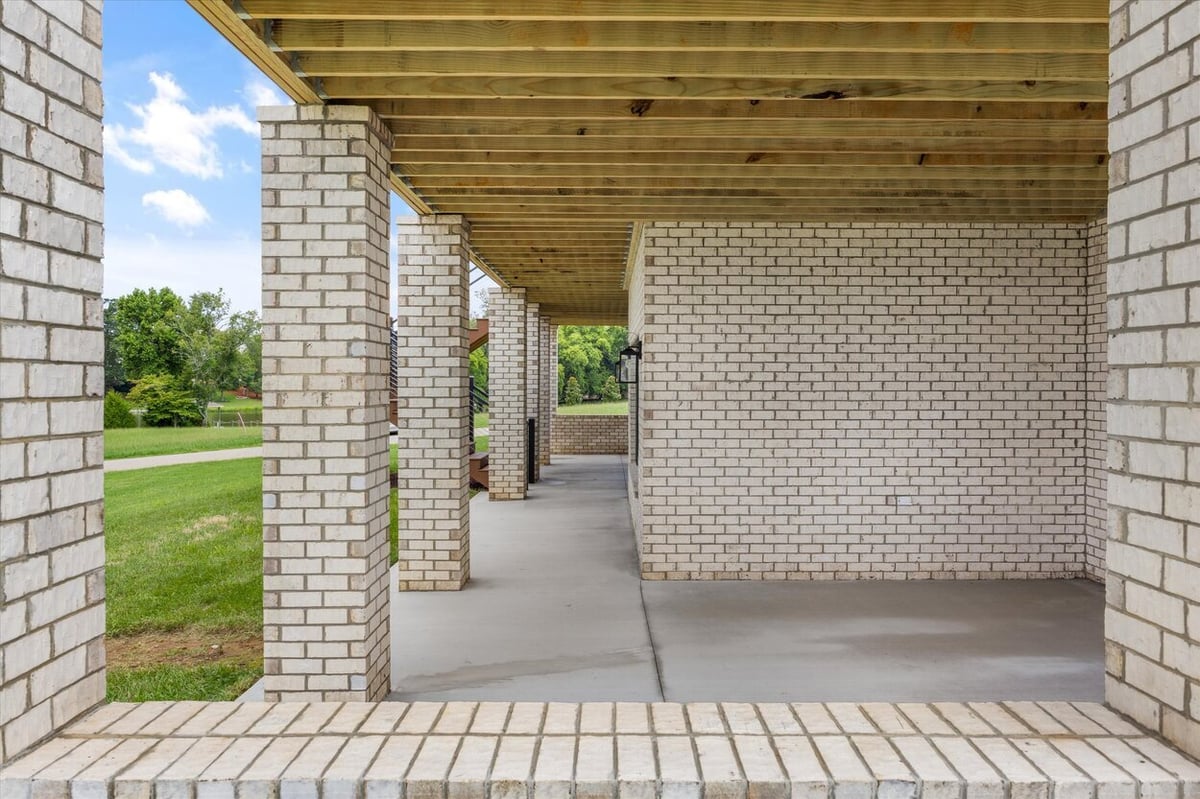Side view of covered patio in a Louisville, TN custom home with exposed beams and white brick columns