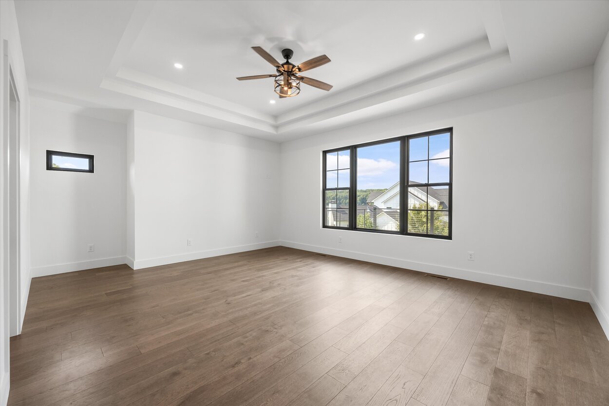 Spacious master bedroom in a Louisville, TN custom home with tray ceiling and large picture window