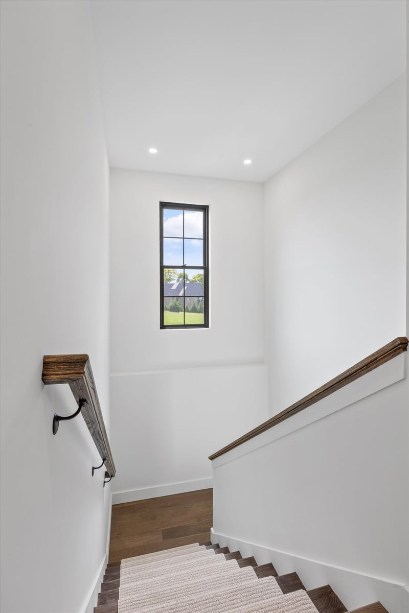 Stairwell in a Louisville, TN custom home with wood railing and tall vertical window