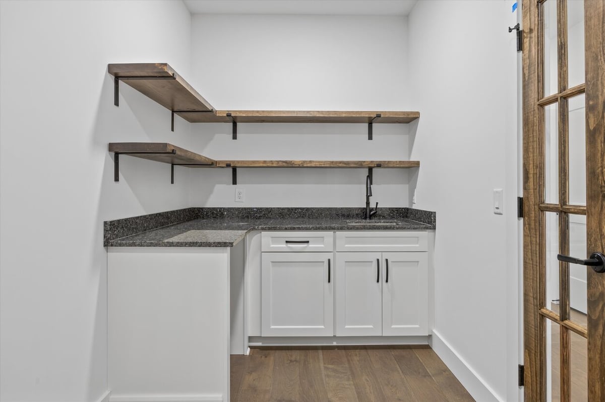 Wet bar or prep space in a Louisville, TN custom home with white cabinetry and floating wood shelves