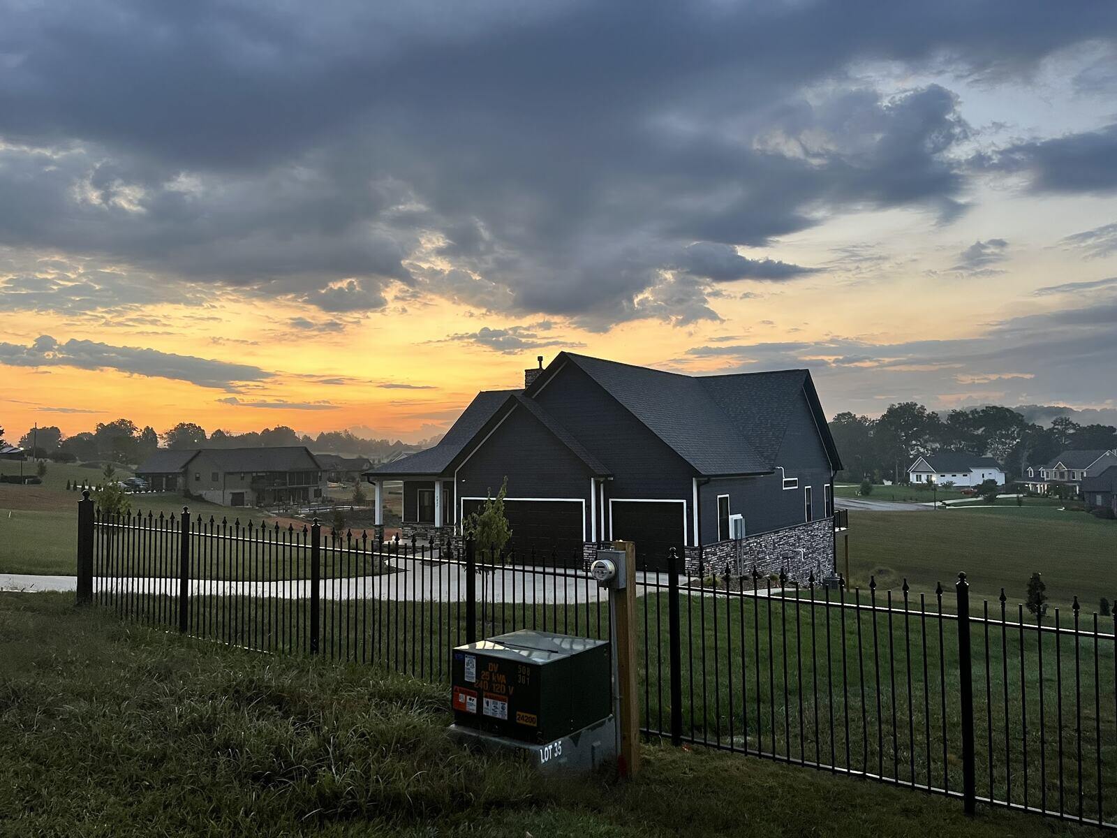 Custom-built modern home by Debuty Builders in Knoxville, TN, at sunrise with a fenced yard