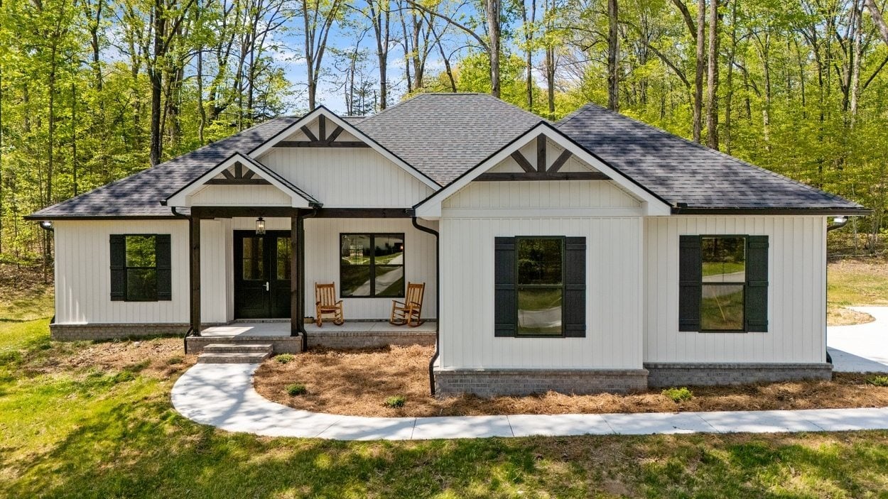 White farmhouse with black trim set in wooded lot in Vonore custom home in Knoxville, TN